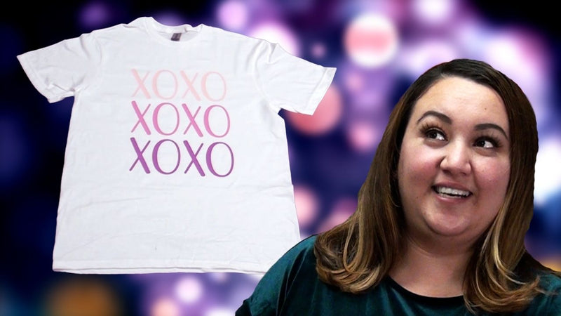 A woman looks up with awe & wonder at a shirt with lettering that reads "XOXO" using different colors of Siser EasyWeed Stretch Heat Transfer Vinyl.